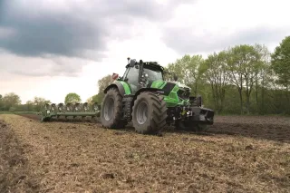 Zelený traktor Deutz-Fahr 7 TTV při práci na poli