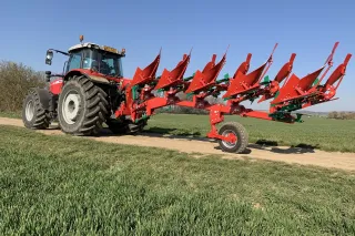 Červený traktor s pluhem Sukov na polní cestě