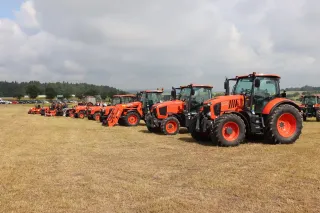 Řada oranžových traktorů Kubota vystavených na polním dni