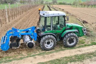 Zelený malotraktor Ferrari s modrým nářadím ve vinici