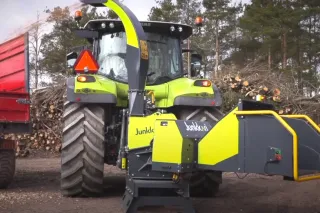 Štěpkovač Junkkari připojený k traktoru vedle přívěsu