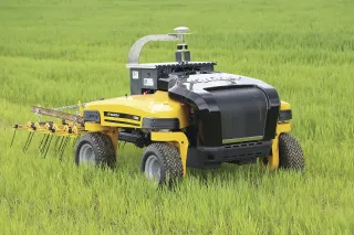 Žlutý autonomní polní robot s bránami APV v zeleném porostu