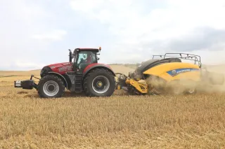 Traktor Case IH s lisem New Holland na sklizeném poli