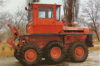 Oranžový traktor DT-75 se třemi koly na každé straně.