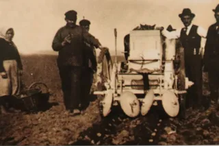 Historický potažní dvouřádkový sazeč brambor při práci na poli.