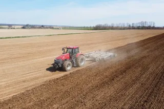 Červený traktor Case IH zpracovává půdu na poli
