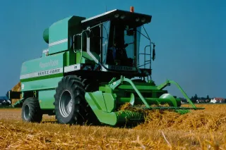 Zelený lis Deutz-Fahr při práci na poli.