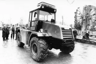 Historický černobílý snímek traktoru Kamaz vystaveného před budovou.