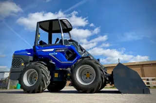 Modrý kloubový nakladač MultiOne s přední lopatou na betonové ploše.