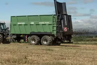 Zelené rozmetadlo Brantner Power Push+ rozhazuje hnůj na poli.