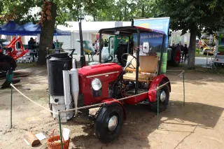 Červený historický traktor Škoda s generátorem dřevoplynu na výstavě.
