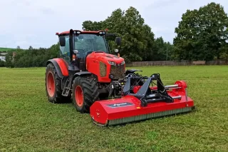 Červený traktor Kubota M6002 s mulčovačem na travnaté ploše.