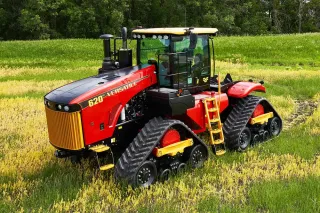 Červený pásový traktor Versatile stojí na poli.