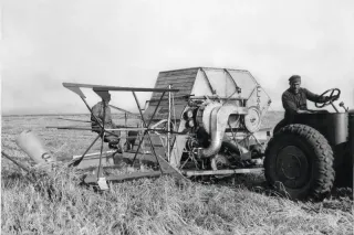 Historická černobílá fotografie sklízecí mlátičky Claas MDB při práci na poli.