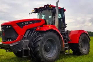 Červený traktor Kirovec stojí na travnaté ploše.