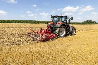 Traktor s červeným diskovým podmítačem Horsch Joker CT na strništi.