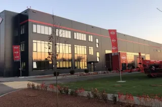 Výrobní budova firmy Kuhn s vystavenou červenou zemědělskou technikou.