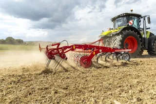 Traktor s červeným kypřičem Horsch Finer pracuje na poli.