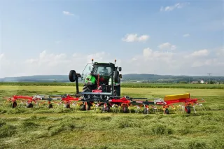 Traktor s širokým obracečem ROZMITAL na louce.