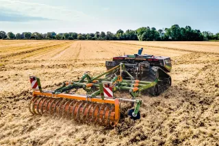 Autonomní pásový polní robot AgXeed s nářadím Amazone na strništi.