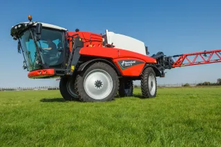 Červený samojízdný postřikovač Kverneland iXdrive na louce.
