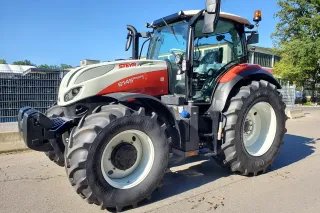 Bíločervený traktor Steyr 6145 Profi s pneumatikami Continental před budovou.