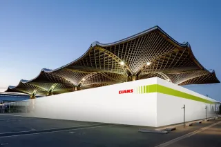 Výstavní pavilon CLAAS s výraznou střechou v podvečerním světle.