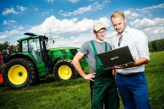 Dva muži u traktoru John Deere si prohlížejí notebook Agricon.