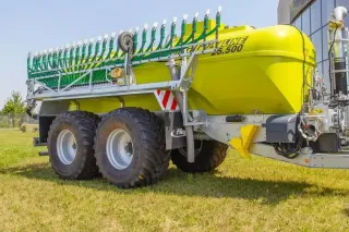 Zelenožlutá cisterna Fliegl PolyLine odstavená na trávníku.
