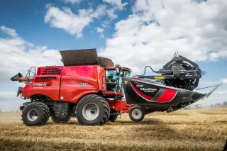 Červená sklízecí mlátička Case IH s adaptérem MacDon na poli.
