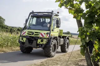 Zelený Mercedes-Benz Unimog stojí u pole.