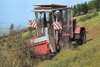 Červený svahový speciál Kabar 132 s předním pracovním adaptérem na stráni.