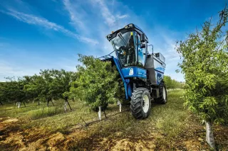 Modrý sklízecí stroj New Holland Braud 11.90 X Multi v sadu.