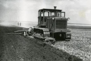 Historický sovětský pásový traktor při orbě pole.