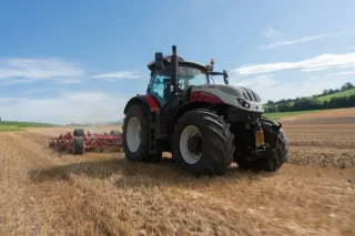 Bíločervený traktor Steyr Terrus CVT pracuje na poli.
