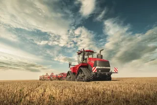 Červený pásový traktor Case IH Quadtrac AFS Connect při práci na poli.
