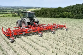 Traktor s červenými prutovými branami Einböck AEROSTAR-FUSION na poli.
