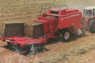 Červený lis Hesston na hranolové balíky při práci na poli