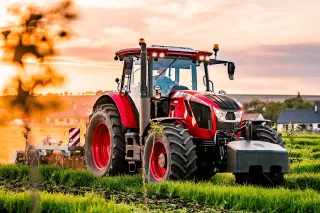Červený traktor Zetor při práci na poli za soumraku