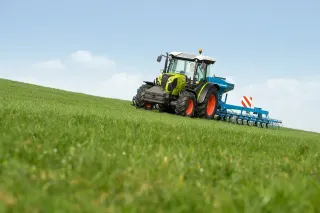 Zelený traktor CLAAS na louce