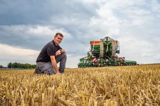 Muž stojící u stroje Amazone pod zataženou oblohou