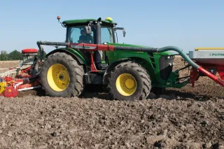 Traktor John Deere se secím strojem Pöttinger AEROSEM na poli