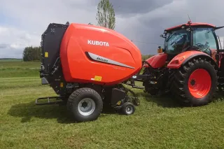 Červený lis na kulaté balíky Kubota BV 5160 na poli