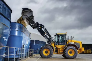 Žlutý kolový nakladač JCB 457S při nakládání siláže