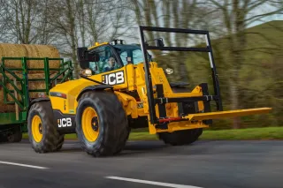 Žlutý teleskopický nakladač JCB 542-70 AGRI Pro u balíků