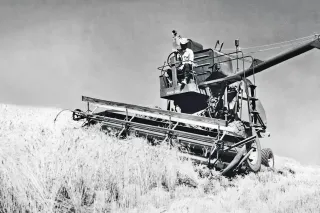 Historická černobílá fotografie sklízecí mlátičky John Deere