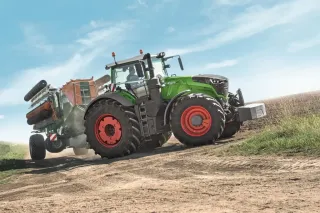 Zelený traktor Fendt s připojeným strojem na poli