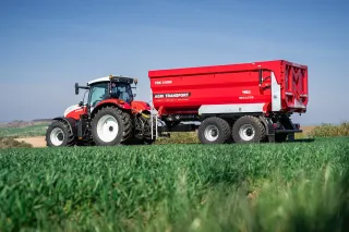 Červený traktor s návěsem Agri Transport TDK 21000 na poli
