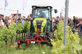 Traktor CLAAS NEXOS při ukázce práce ve vinici za přítomnosti diváků.