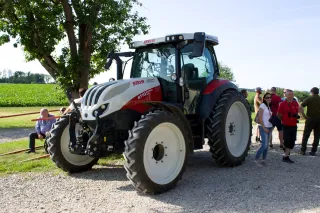 Traktor Steyr u farmy s návštěvníky vedle stroje.